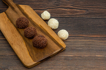 brazilian brigadeiro and beijinho traditional delicious chocolate dessert, party snacks, sweet sprinkle background top view over wooden table