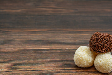 brazilian brigadeiro and beijinho traditional delicious chocolate dessert, party snacks, sweet sprinkle background top view over wooden table