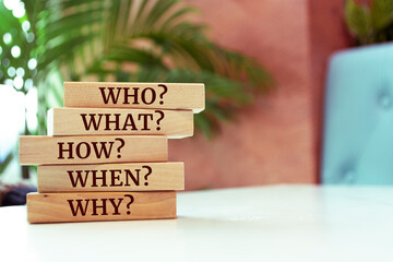 Wooden blocks with words 'Who?, What?, How?, When?, Why?'. questions.