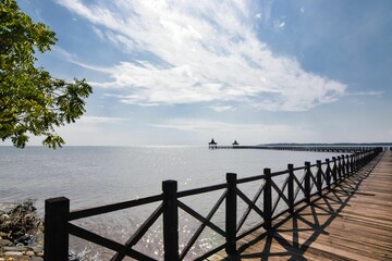 Obraz premium Old wooden pier in front of the see with a beautiful cloudy sky in the background