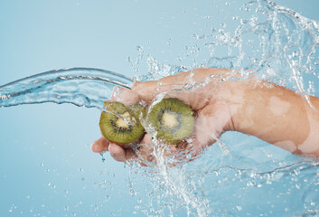 Hands, beauty and kiwi in a studio with splash for skincare, shower and organic treatment against a...