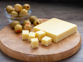 Montery Jack cheese with olives on wooden board