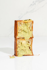 Two halves of flaky sweet cube croissant with pistachio custard and nut crumbs