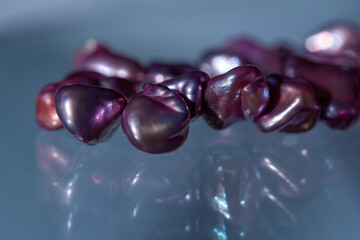 Macro abstract texture background of a necklace containing deep pink color baroque pearls with natural imperfections, on a translucent glass surface