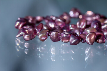 Macro abstract texture background of a necklace containing deep pink color baroque pearls with natural imperfections, on a translucent glass surface