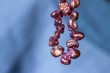 Macro abstract view of a necklace containing deep pink color baroque pearls with natural...