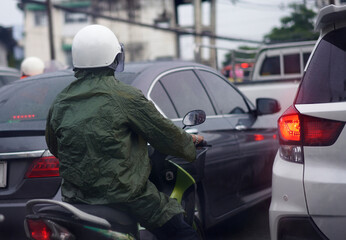 motorcycle driver on raincoat ride in traffic rain road