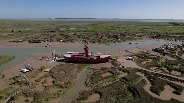 Aerial view away from a stranded LV15 Trinity Lightvessel, sunny Tollesbury, UK - pull back, drone shot