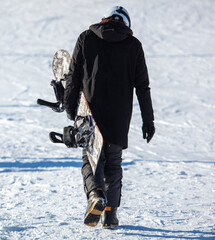 Fototapeta na wymiar A man walks with a snowboard in his hands.