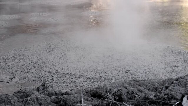 Rising steam and small bubbles along the shore of Wai-o-tapu hot mud pools in New Zealand. Steady close-up footage