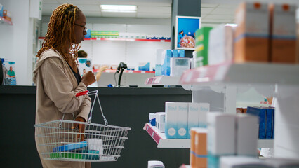 Medical worker analyzing supplements boxes on drugstore shelves to help clients with treatment and medicine. Looking at pharmaceutics and taking notes, working in pharmacy store.