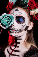 Studio shot of santa muerte with skull make up, looking glamour with flowers crown and body art. Celebraing day of the dead mexican holiday with roses and creepy festival tradition.