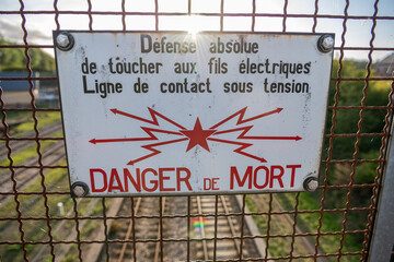 Panneau d'avertissement Sncf sur un grillage au dessus des voies ferrées : Défense de toucher aux fils, danger de mort - obrazy, fototapety, plakaty