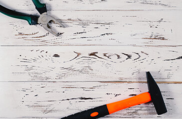 Hammer and pliers on a light wooden background.