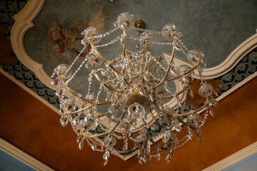 Manetin, Czech Republic, 23 July 2022: Castle chateau representative interior with baroque wooden carved furniture, beautiful crystal chandelier with pendants, Vintage strass lamp