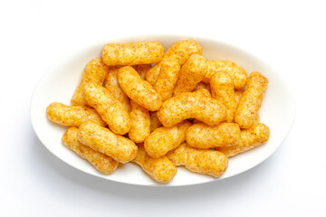Peanut flips, in a white bowl. Also known as Bamba, peanut puffs or snips, is a puffed, peanut-flavored corn snack, with a peanut content up to a third. Close-up, from above, macro food photo.