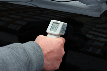 Checking the thickness of car paint using an electronic sensor. Car paint thickness check.