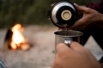 Pour from a thermos. Woman pours coffee into a cup for man. Tourism and travel concept. Autumn photos.