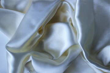White silk, folded in beautiful folds. Solid fabric background. Silk, satin or satin.