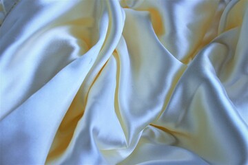 White silk, folded in beautiful folds. Solid fabric background. Silk, satin or satin.