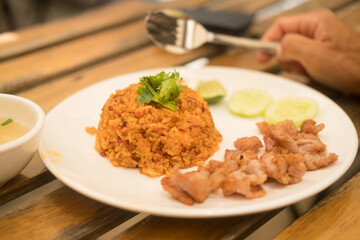 Thai spicy shrimp paste fried rice served with fried pork served on a white dish. Selective focus