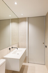 Fototapeta na wymiar Vertical view of narrow minimalist bathroom. Big mirror and white sink with black faucet.