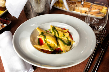 Pasta triangles ravioli or pansotti stuffed with cheese and served with tomato and basil pesto sauce. Life style photo, italian restaurant food.
