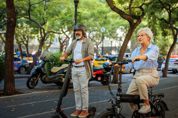 Obraz premium Senior couple riding electric bike and scooter.