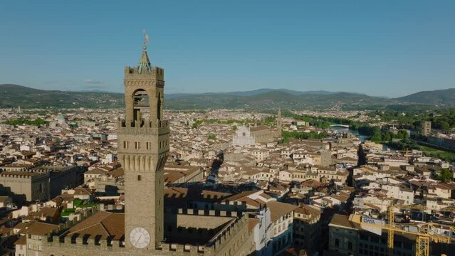 Forwards fly around old and famous Palazzo Vecchio and its tall tower. Aerial view of historic city centre. Florence, Italy