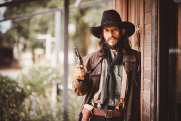 Portrait cowboy wearing in western style suite with hat posing show gun or  retro cowboy weapon is...