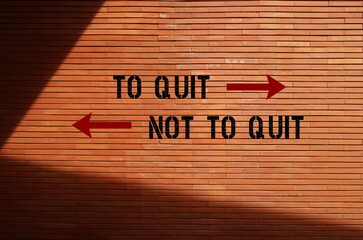 Brick wall background with inscription opposite direction signs TO QUIT or NOT TO QUIT, means to...