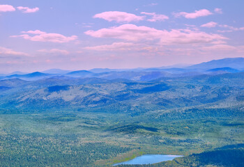 Fototapeta premium Mountain valley with blue lake among deep forests in pink morning light - idyllic summer landscape. Mountain peaks under blue morning mist and pink clouds on background, Sheregesh resort, top view