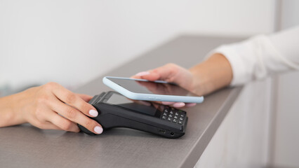 A woman pays using a contactless payment of the NFC used by a smartphone. 