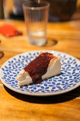 Vertical view of a piece of cheesecake with strawberry jam served on a blue-patterned plate