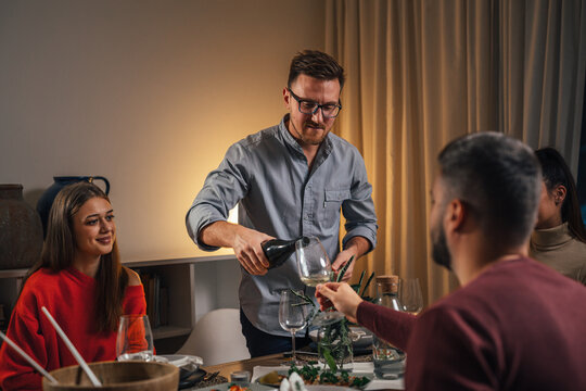 Man Serving Wine To Guests At Dinner Party