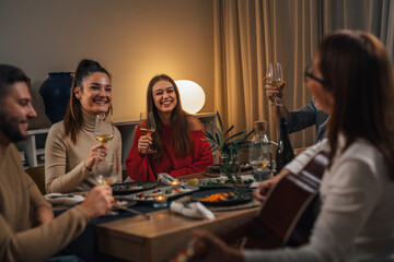 friends singing and playing guitar on gathering on home dinner party