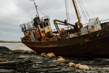 Abandoned metal ship on the seashore and the lines of the cloudy dark sky. Beautiful places
