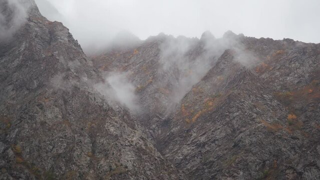 4K shot of fog around the mountain peaks during the stormy weather at Tandi in Lahaul Spiti district at Himachal Pradesh, India. Clouds rolling over the peaks of the mountain. Nature background. 