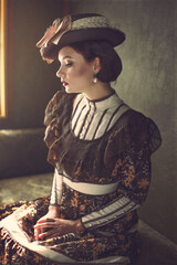 Very beautiful woman in a vintage suit and hat sits in a compartment of a retro train near the window