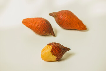 Snake fruit is a fruit that has a sweet and sour taste. Peel one fruit on a white background.