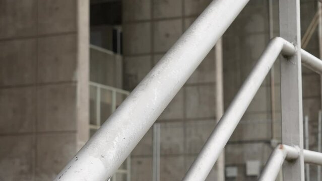 Galvanized steel street handrail on concrete building wall background closeup