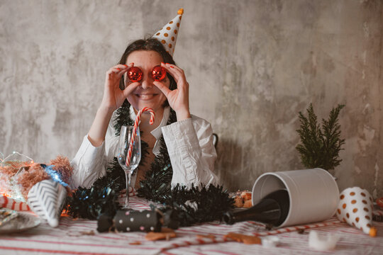 Young cheerful woman in festive party hat comically covering her eyes with Christmas shining bubbles