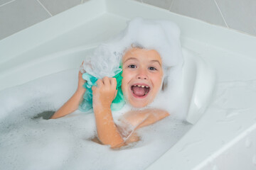 Children bathing. Kid in a bath tub. Washing in bath with soap suds on hair. Child taking bath. Closeup portrait of smiling kid, health care and kids hygiene. Kids face in bath tub with foam. - obrazy, fototapety, plakaty