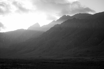 Foggy sunset view over the dark mountains, grayscale
