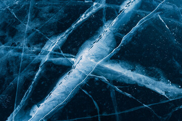 Transparent blue ice with cracks on winter Baikal lake. Abstract winter background