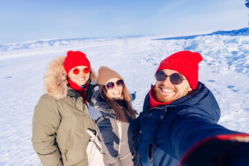 Group happy tourists on background of ice winter lake Baikal on sunny day
