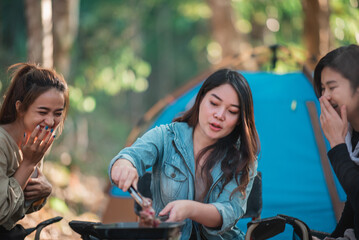 Young women cooking and use smartphone take photo on camping