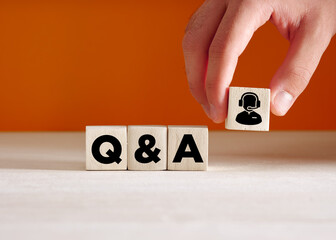 Business support service. Hand puts the wooden cube with the acronym Q&A questions and answers.