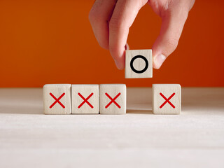 Hand puts the wooden cube with O symbol next to the cubes with X symbols. Correct and incorrect mindset