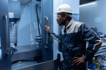 Professional african american engineer working on CNC machinery, blue toning. Concept industry factory people